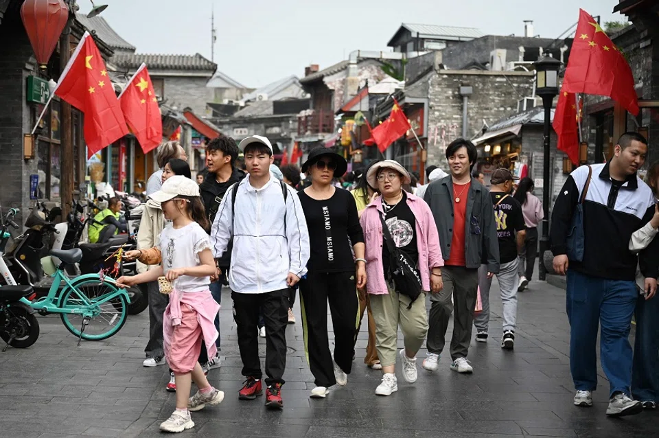 People walk in a shopping area in Beijing, China, on 4 May 2024. (Greg Baker/AFP)