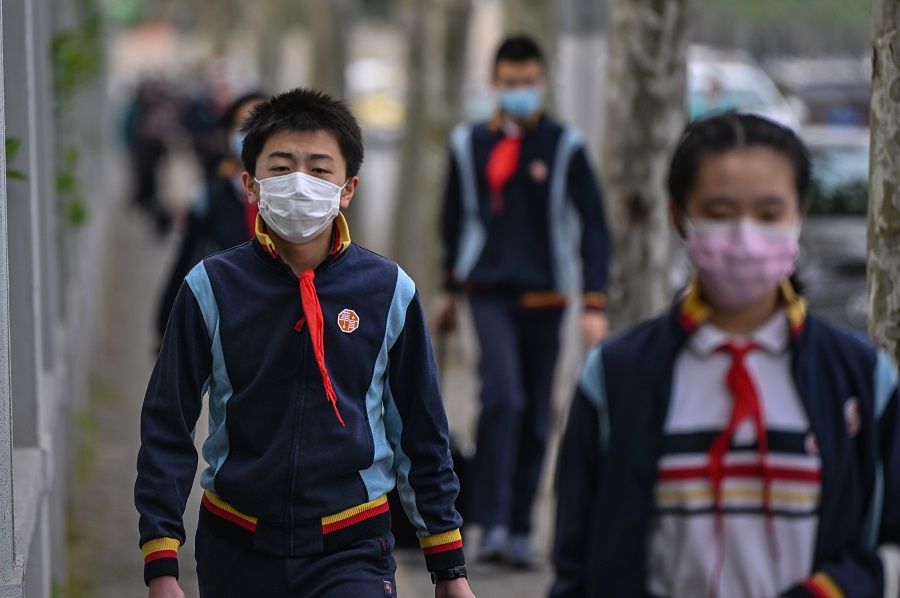 A short poem published in a widely circulated middle school student newspaper recently sparked debate. In this photo taken on 27 April 2020, students wearing face masks arrive at a middle school in Shanghai. (Hector Retamal/AFP)