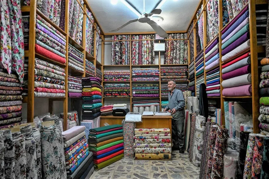 A fabric seller stays inside his shop at a bazaar near Balikligol (or Pool of Abraham, Halil-Ur Rahman Lake), in Sanliurfa, Turkey, on 27 April 2023. (Ozan Kose/AFP)