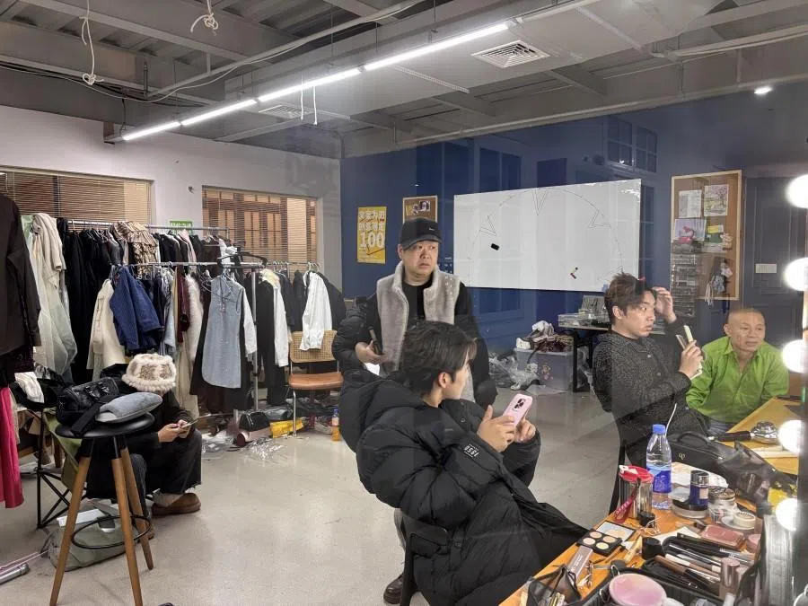 Cast and crew work on hair, makeup and clothes.