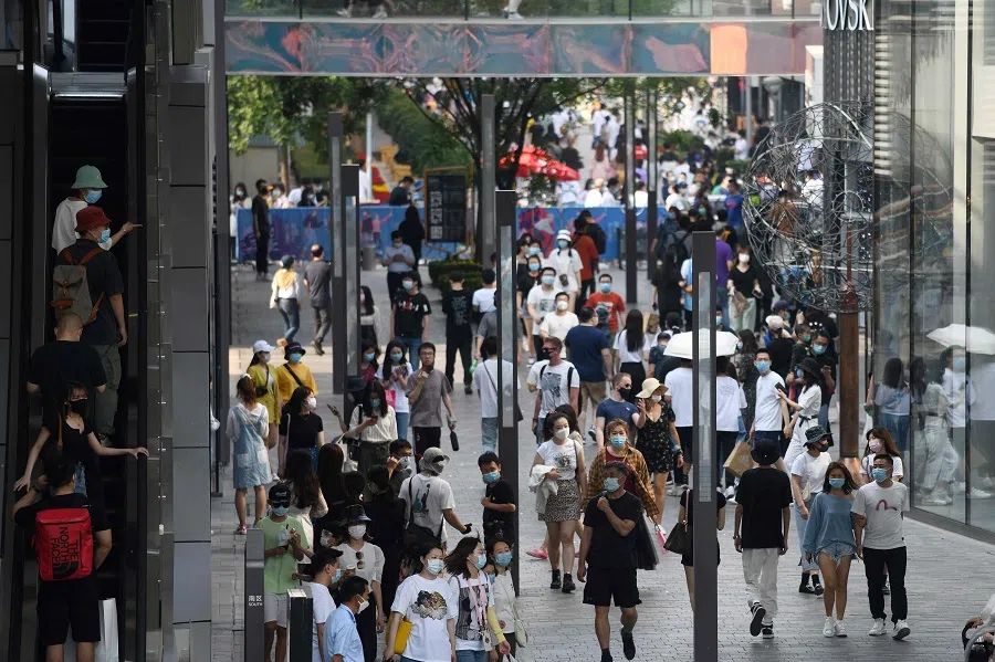 People wear face masks as a preventive measure against the Covid-19 coronavirus as they walk through a shopping mall in Beijing on 2 May 2020. (Greg Baker/AFP)