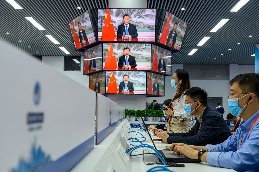 Media staff work next to screens showing live images of Chinese President Xi Jinping speaking during the opening ceremony of the China International Import Expo (CIIE), at the media center of the Expo in Shanghai, China on 4 November 2021. (AFP)