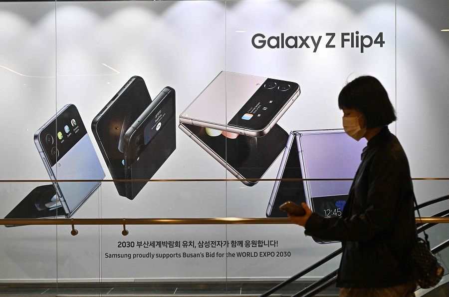A woman walks past an advertisement for the Samsung Galaxy Z Flip4 smartphone at the company's Seocho building in Seoul, South Korea, on 7 October 2022. (Jung Yeon-je/AFP)