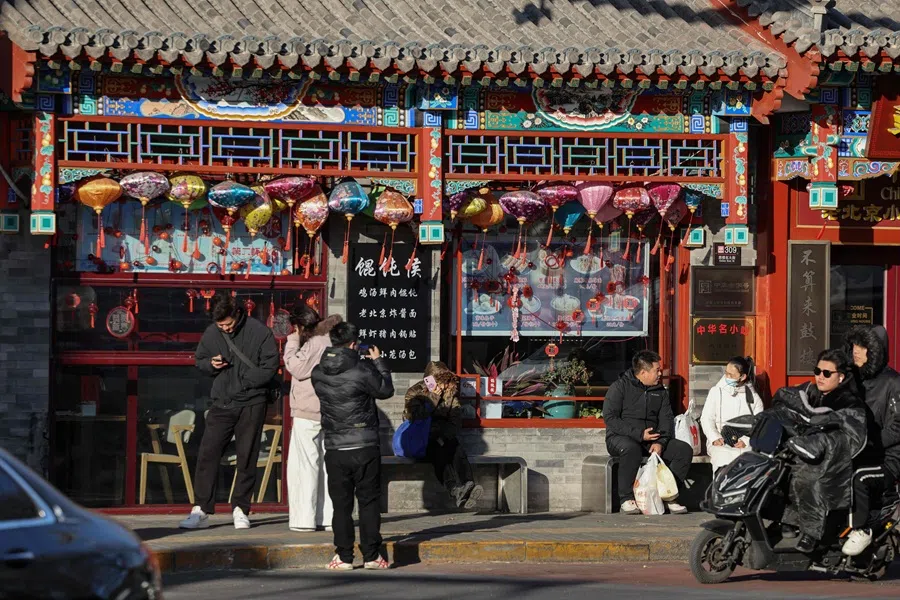 People are seen on a street in Beijing on 2 December 2025. (Ludovic Marin/AFP)