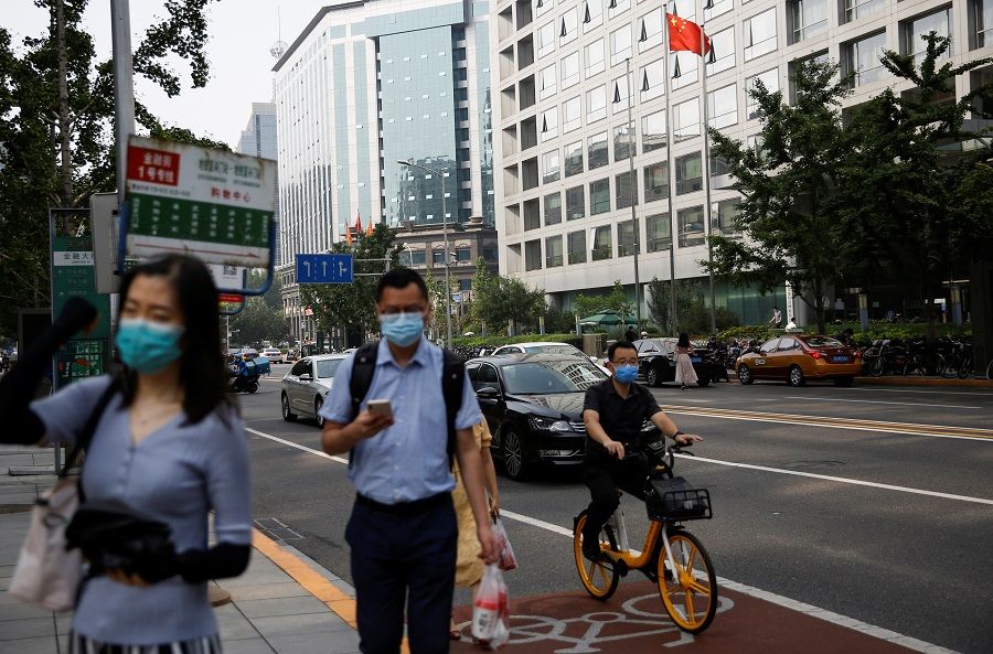 People wearing face masks following the Covid-19 outbreak walk past a Chinese national flag in front of the building of China Securities Regulatory Commission (CSRC) in Beijing, China, on 16 July 2020. (Tingshu Wang/Reuters)