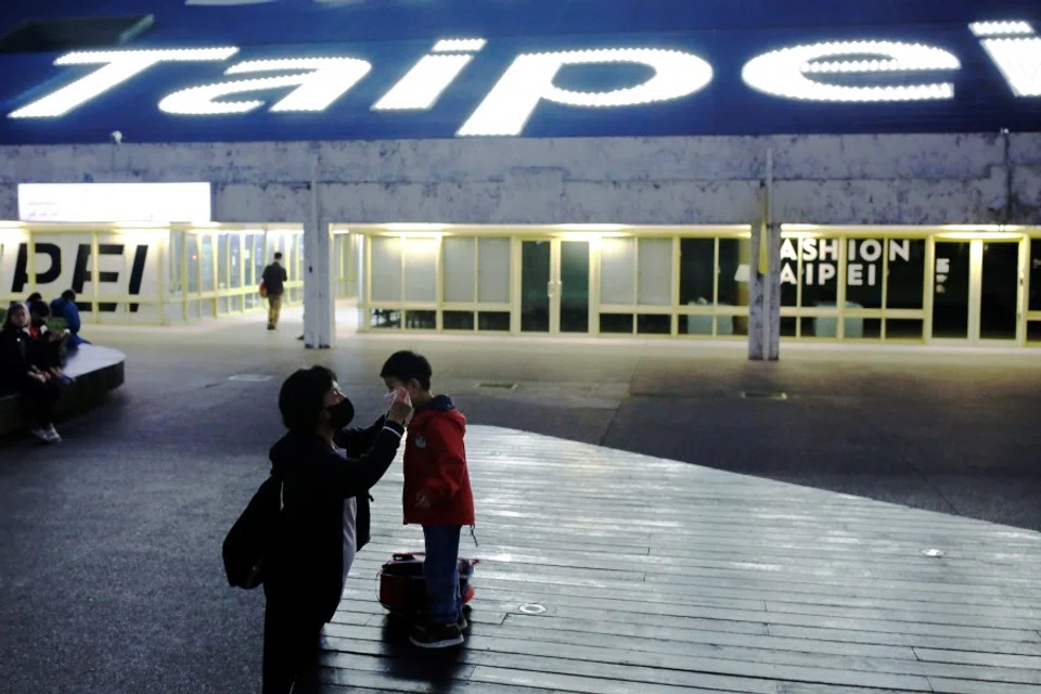 An adult helps to put a face mask on a child in Taipei, March 31, 2020. (Ann Wang/REUTERS)