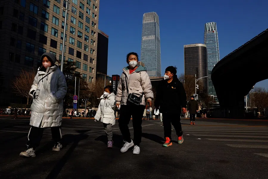People walk on a street in Beijing's central business district during morning rush hour in Beijing, China, 30 January 2023. (Tingshu Wang/Reuters)