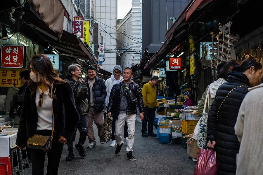 People walk past market stalls at Namdaemun Market in Seoul, South Korea, on 26 March 2024. (Anthony Wallace/AFP)
