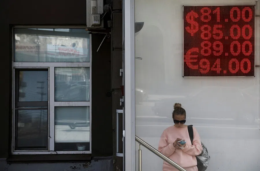 A woman stands next to a board showing currency exchange rates of the euro and the US dollar against the Russian rouble in Moscow, Russia, 7 April 2023. (Maxim Shemetov/Reuters)