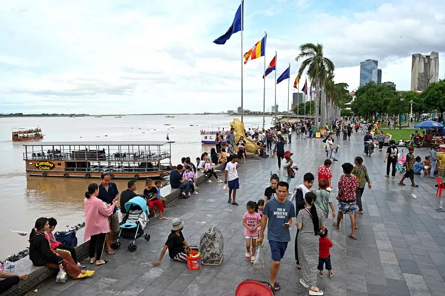People walk at a riverside near the Royal Palace in Phnom Penh, Cambodia, on 24 July 2023. (Tang Chhin Sothy/AFP)