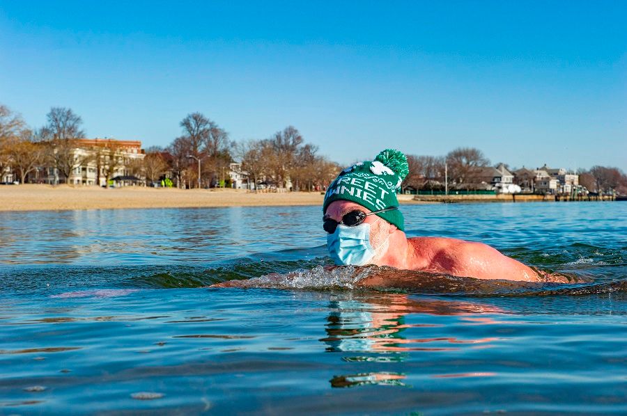 A member of the L-Street Brownies makes his way back to shore with a hat on and a mask during the annual polar bear plunge at the M Street beach in Boston, Massachusetts, US, on 1 January 2021. (Joseph Prezioso/AFP)