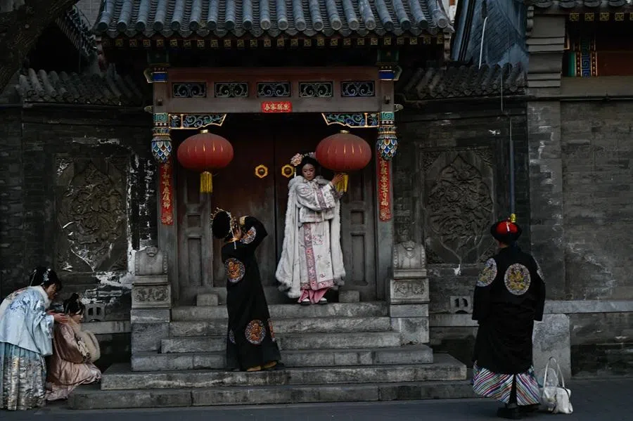 People wearing traditional costumes pose for pictures in a tourist area of Beijing on 8 February 2026. (Pedro Pardo/AFP)