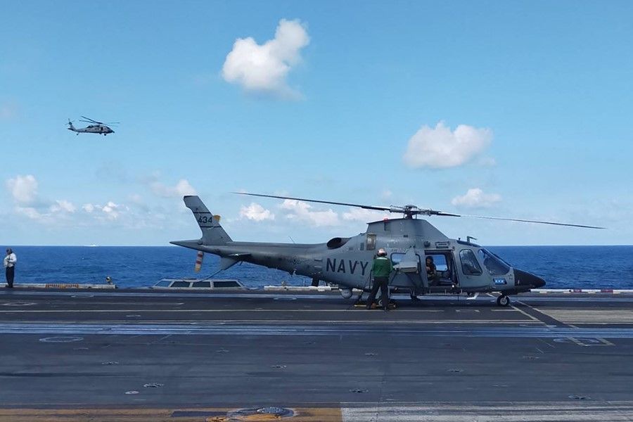 This handout photo from the Armed Forces of the Philippines taken on 4 January 2024 shows a pilot executing a final check in a Philippine Navy AW109 helicopter on the deck of the USS Carl Vinson during the second iteration of the Armed Forces of the Philippines and the US Indo-Pacific Command Military Cooperative Activity in the South China Sea. (Handout/Armed Forces of the Philippines/AFP)