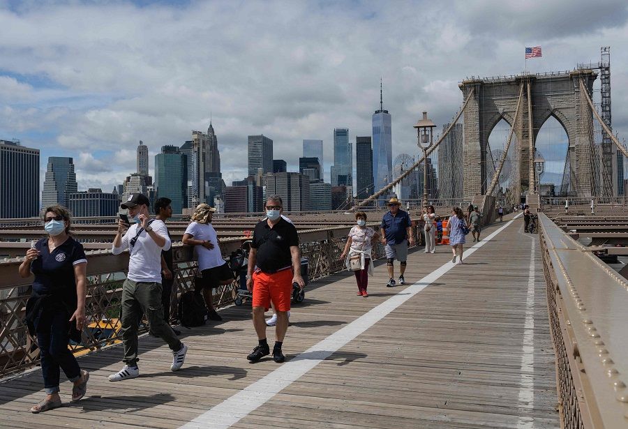 People walk over the Brooklyn Bridge from Manhattan in New York City, US, on 19 August 2021. (Angela Weiss/AFP)