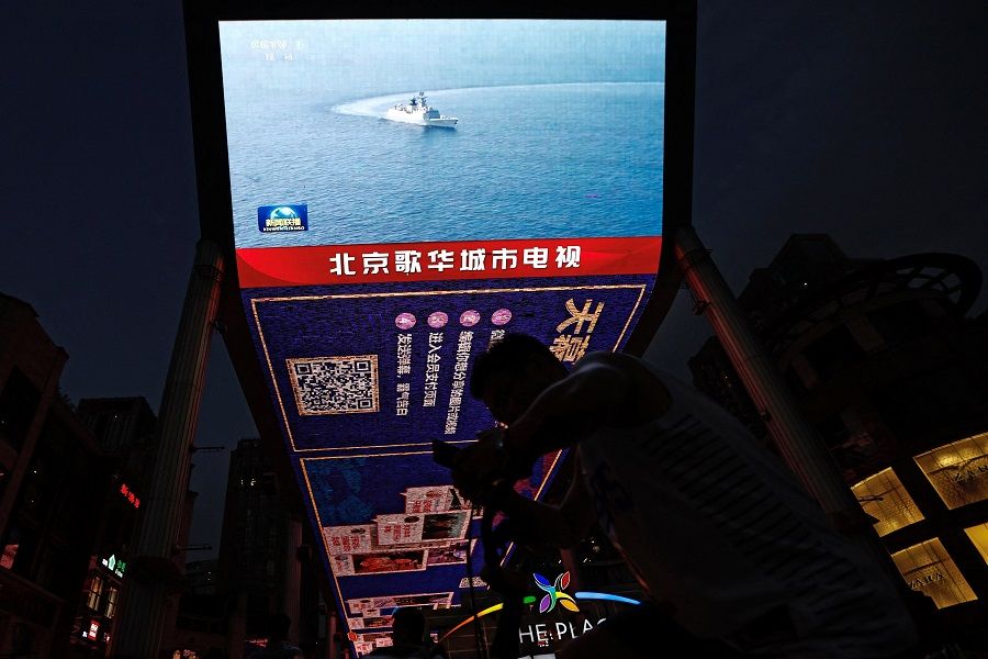 A screen broadcasts news footage of a Navy Force vessel taking part in military drills by the Eastern Theatre Command of China's People's Liberation Army (PLA) around Taiwan, in a shopping area in Beijing, China, 19 August 2023. (Tingshu Wang/Reuters)
