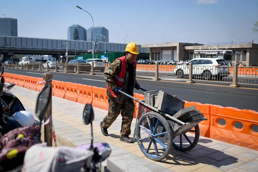 A worker helps pave a sidewalk in Beijing, on 31 March 2025. (Wang Zhao/AFP)