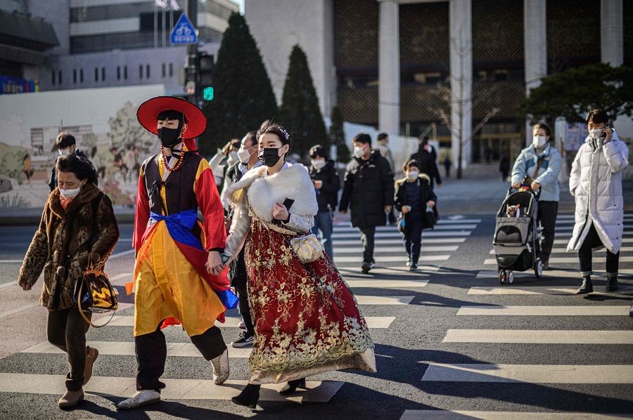 A couple (front, left) wear traditional hanbok dress as they walk across a road in Seoul, South Korea, on 7 January 2022. (Anthony Wallace/AFP)