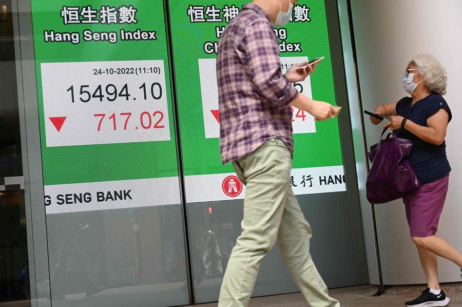 Pedestrians pass a sign showing the numbers for the Hang Seng Index in Hong Kong on 24 October 2022. (Peter Parks/AFP)