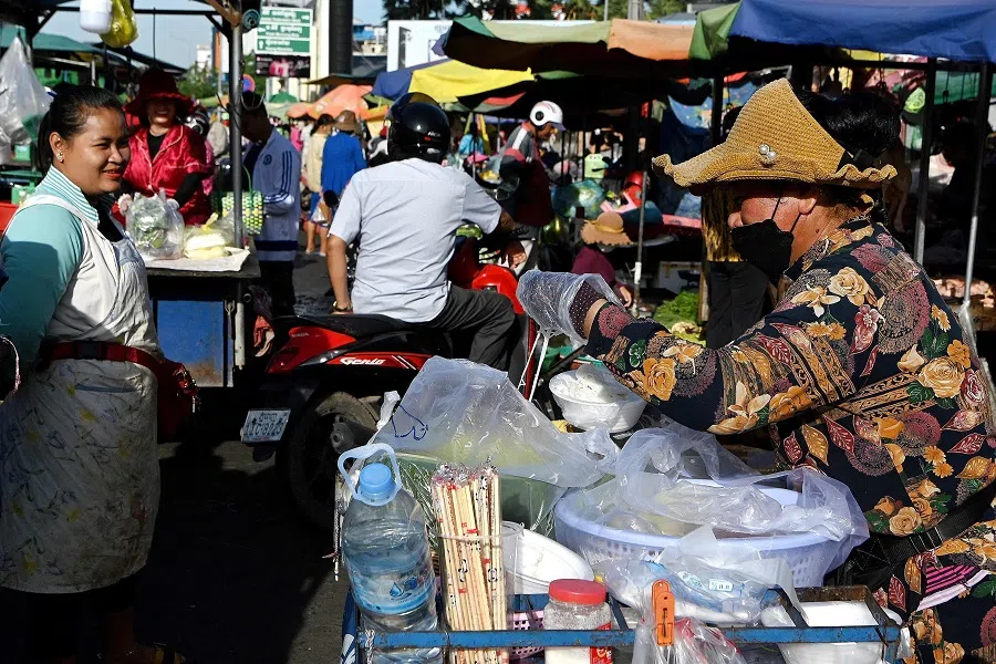 A vendor (right) prepares "Khmer noodles" for customers at a street market in Phnom Penh, Cambodia, on 29 June 2022. (Tang Chhin Sothy/AFP)