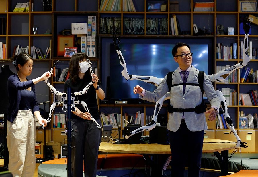 Staff members control the robot arm control unit synced with wearable robot arms "Jizai Arms", which Masahiko Inami of the University of Tokyo wears during its demonstration at the school's lab in Tokyo, Japan, 22 June 2023. (Kim Kyung-Hoon/Reuters)