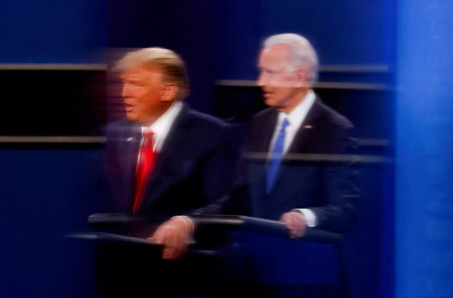 Donald Trump and Joe Biden are reflected in the plexiglass in a photo taken on 22 October 2020. (Mike Segar/Reuters)