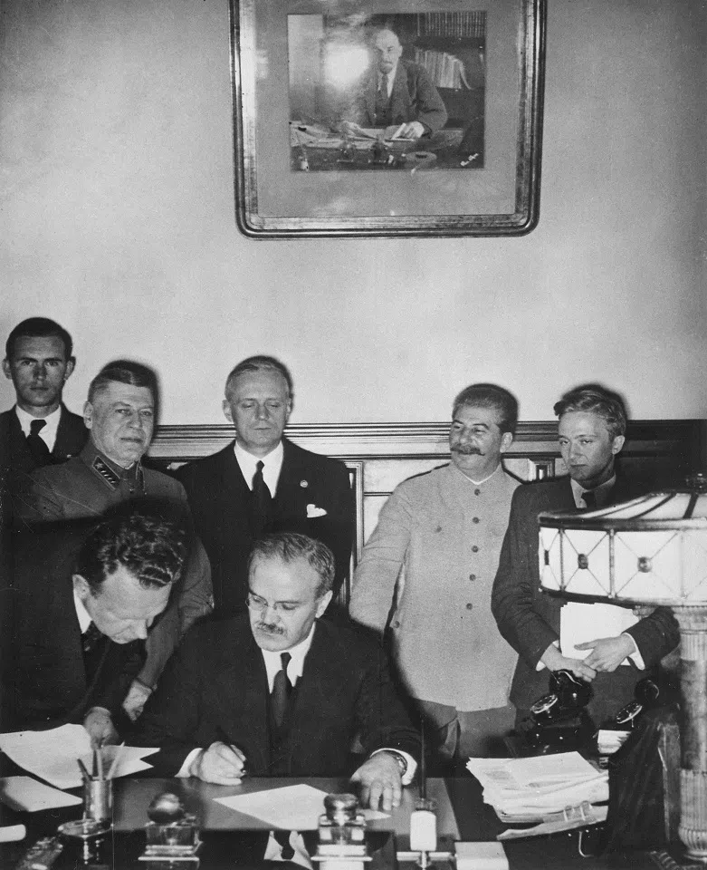 Soviet Foreign Minister Vyacheslav Molotov signs the German–Soviet Treaty of Friendship in Moscow; behind him are Richard Schulze-Kossens (Ribbentrop’s adjutant), Boris Shaposhnikov (Chief of staff of the Red Army), Joachim von Ribbentrop, Joseph Stalin, Vladimir Pavlov (Soviet translator). Alexey Shkvarzev (Soviet ambassador in Berlin), stands next to Molotov. (Wikimedia)