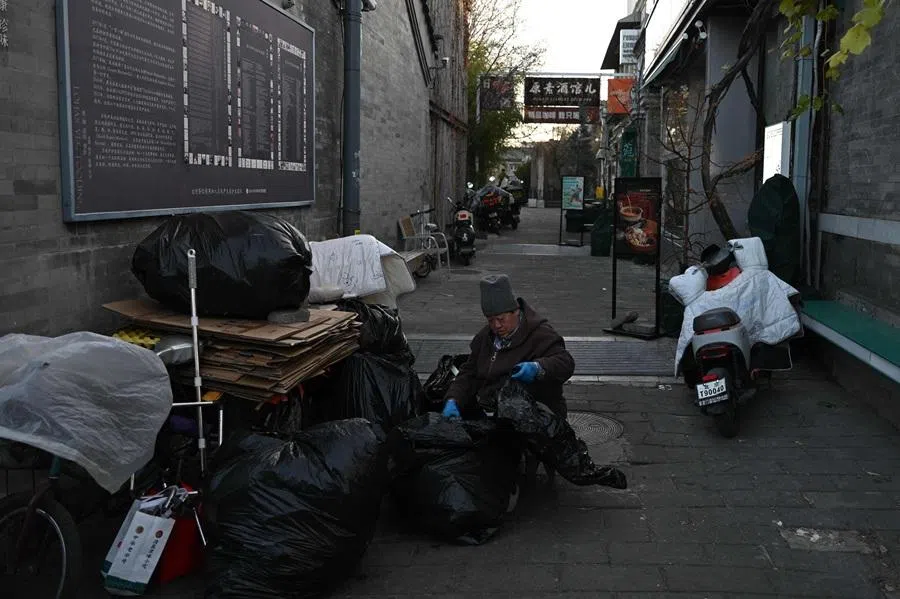 A woman separates trash in an alley in an area popular with tourists in Beijing, China, on 30 November 2025. (Pedro Pardo/AFP)