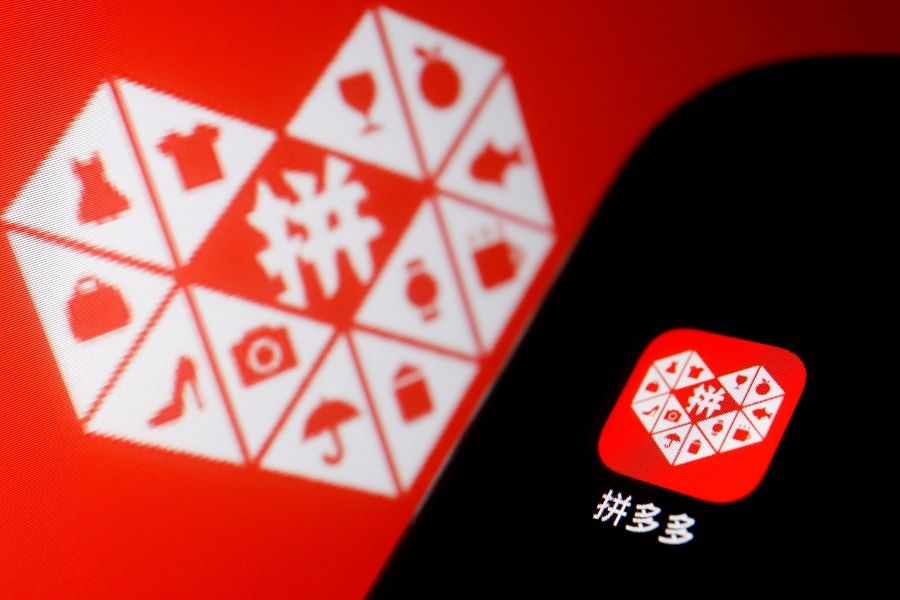 The logo of Chinese e-commerce platform Pinduoduo Inc. is displayed next to a mobile phone, in this illustration picture taken 22 March 2022. (Florence Lo/Illustration/File Photo/Reuters)
