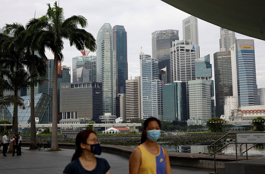 People wearing face masks pass the city skyline, in Singapore, 22 September 2021. (Edgar Su/Reuters)