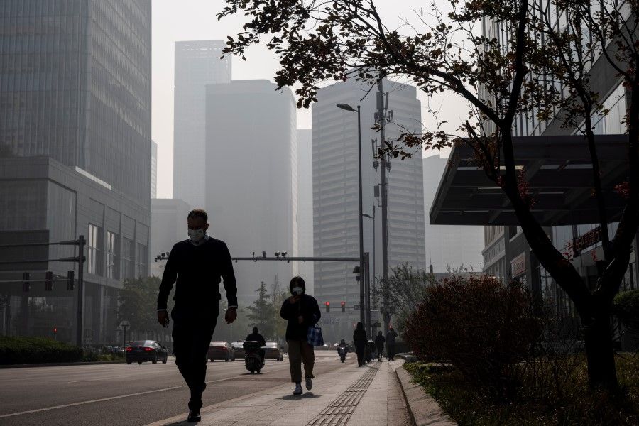 People walk in the Central Business District (CBD) on a hazy morning in Beijing, China, 25 October 2021. (Thomas Peter/Reuters)