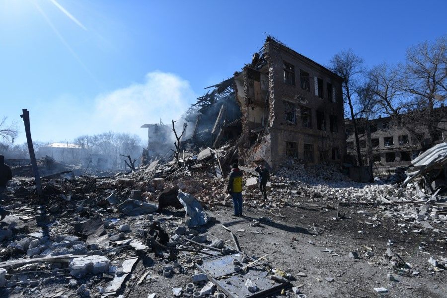 People stand in front of a destroyed shoe factory in the aftermath of a missile attack, amid Russia's invasion, in Dnipro, Ukraine, 12 March 2022. (Mykola Synelnikov/Reuters)
