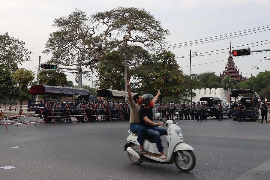 Protesters show the three-finger salute to riot police as protesters hold a demonstration against the military coup near the royal palace in Mandalay, Myanmar, on 7 February 2021. (STR/AFP)