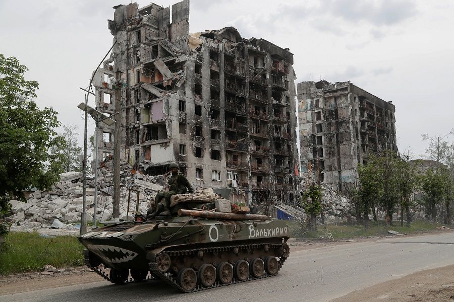 Service members of pro-Russian troops drive an armoured vehicle along a street past a destroyed residential building in the town of Popasna in the Luhansk Region, Ukraine, 26 May 2022. (Alexander Ermochenko/Reuters)