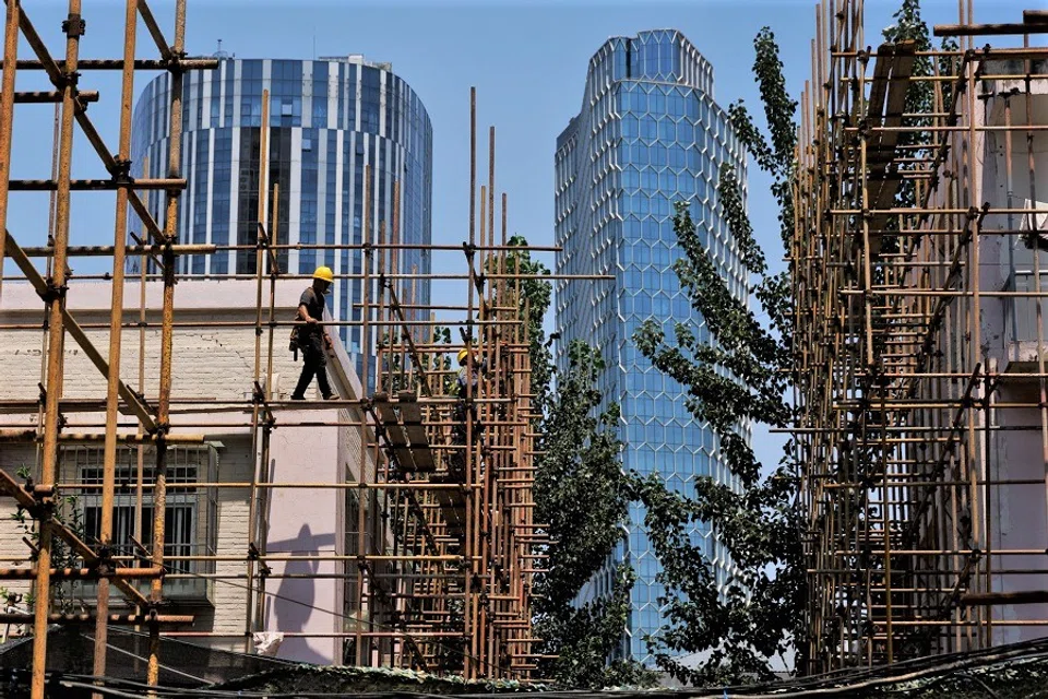 A worker walks on a scaffolding at a construction site of an apartment building under refurbishment in Beijing, China, 20 July 2022. (Thomas Peter/Reuters)