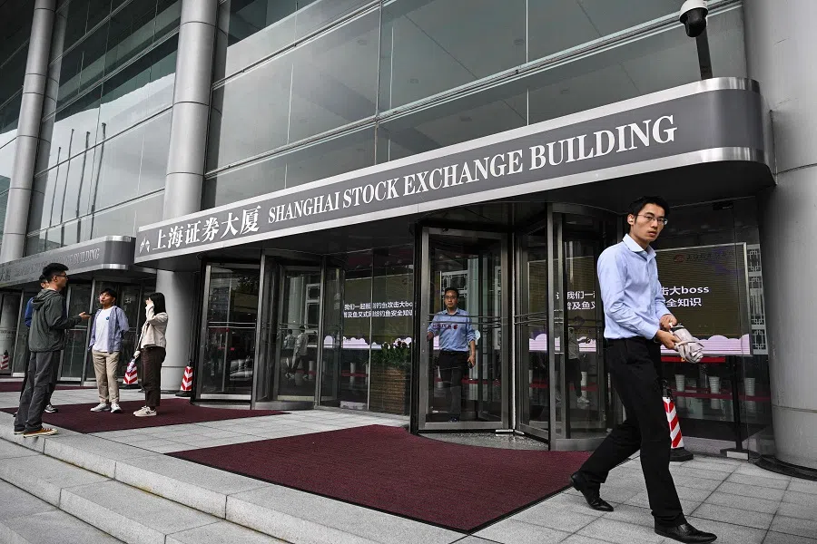 People stand next to an entrance of the Shanghai Stock Exchange in the Pudong district in Shanghai on 5 June 2024. (Hector Retamal/AFP)