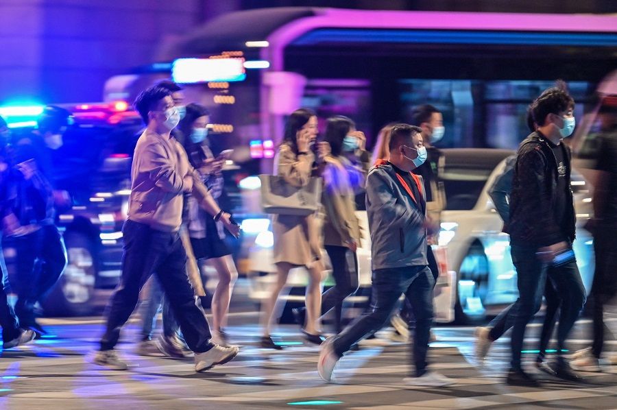 People cross a street on the Bund in Shanghai, China, on 24 October 2022. (Hector Retamal/AFP)