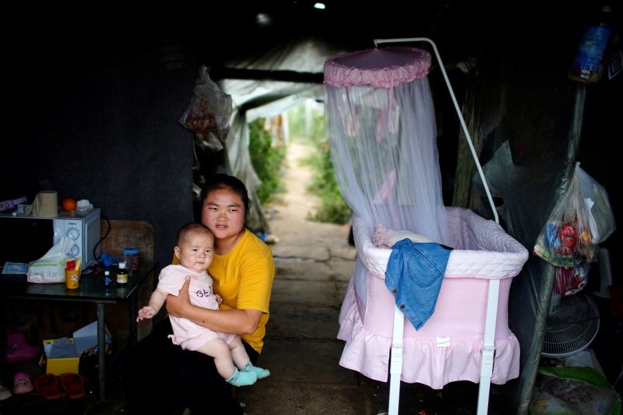 A woman and baby inside a room of a greenhouse at a village on the outskirts of Shanghai, China, 3 June 2021. (Aly Song/Reuters)