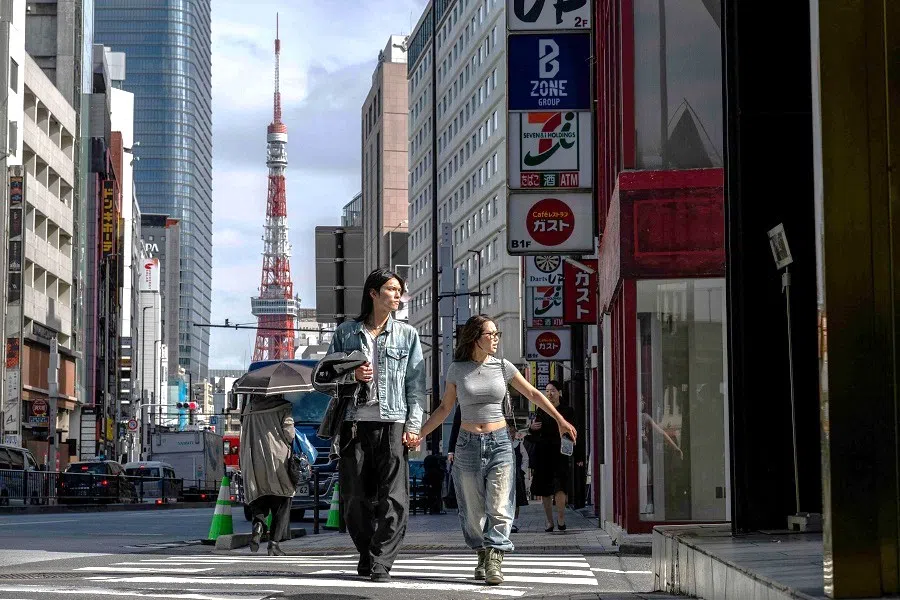 People cross a street as the Tokyo Tower looms in the background in Tokyo, Japan, on 10 October 2024.