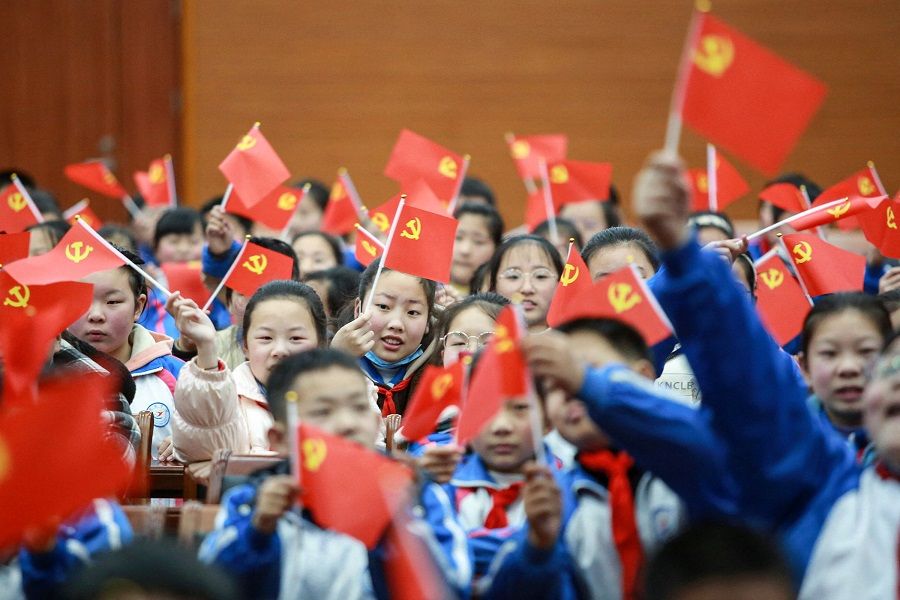 This photo taken on 23 March 2021 shows students waving flags of the Communist Party as they prepare to watch a movie "The Founding of a Party" in Yangzhou, Jiangsu province, China, to mark the 100th anniversary of the founding of the Communist Party of China. (STR/AFP)