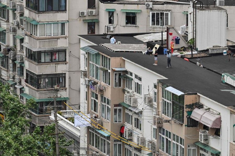 People stand on a rooftop of a building during a Covid-19 lockdown in the Jing'an district in Shanghai on 7 May 2022. (Hector Retamal/AFP)