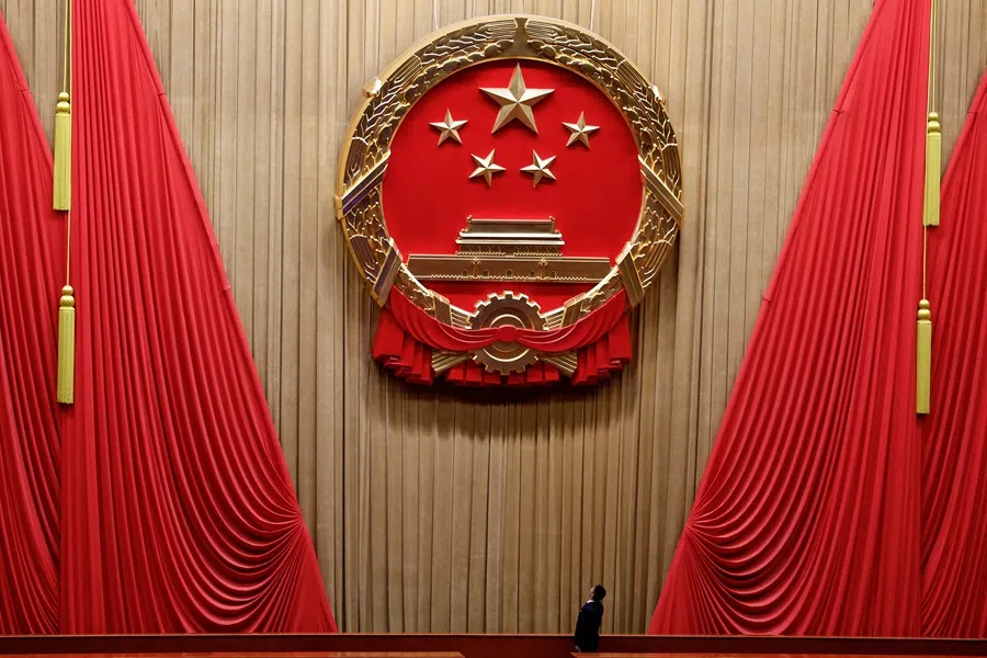A staff member looks at the national emblem before the start of the second plenary session of the National People’s Congress (NPC), at the Great Hall of the People in Beijing, China, on 8 March 2025. (Tingshu Wang/Reuters)