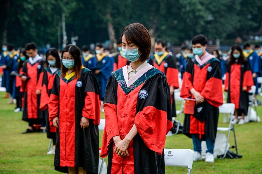 This photo taken on 20 June 2020 shows university graduates standing in silent tribute for victims of the Covid-19 pandemic during their graduation ceremony in Wuhan University in Wuhan, Hubei, China. (STR/AFP)