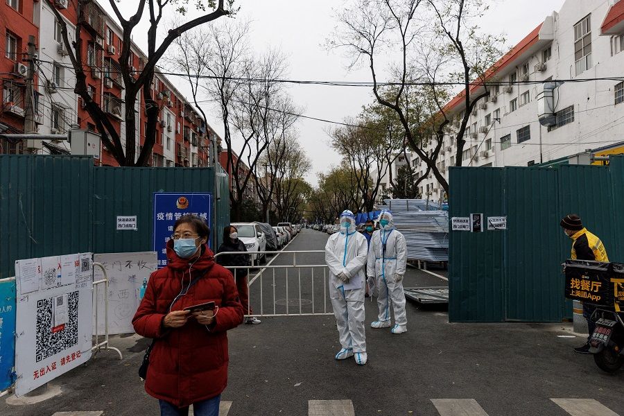 Epidemic-prevention workers in protective suits stand guard at a residential compound as Covid-19 outbreaks continue in Beijing, China, 28 November 2022. (Thomas Peter/File Photo/Reuters)