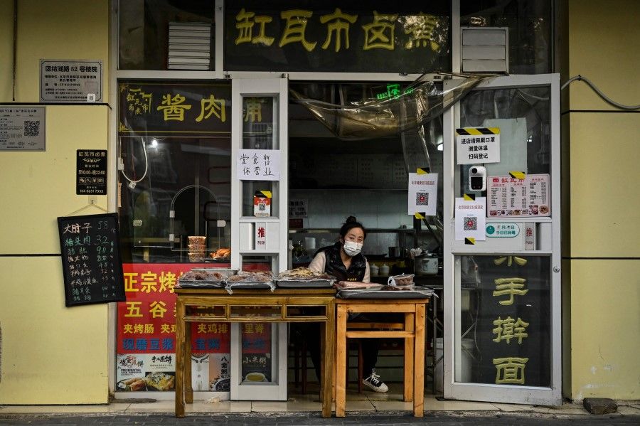 A woman waits for customers at a restaurant with dine-in services suspended in Beijing's Chaoyang district due to Covid-19 restrictions on 19 November 2022. (Jade Gao/AFP)