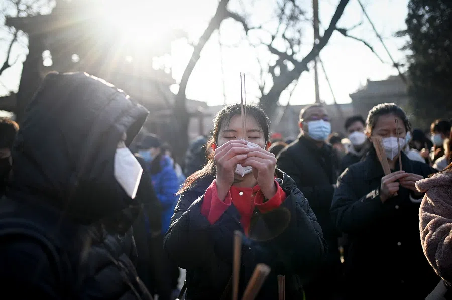A woman holding incense sticks prays at the Lama temple, in Beijing, China, on 1 January 2023. (Wang Zhao/AFP)
