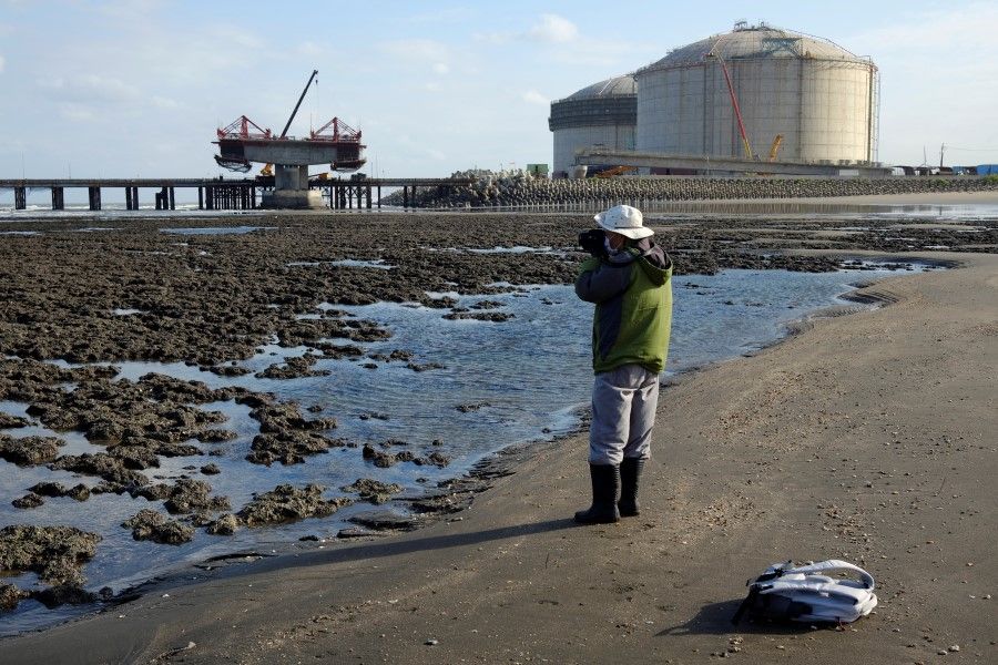 A woman photographs a planned liquefied natural gas (LNG) terminal near the algal reef coast of Datan, ahead of a referendum on whether to relocate the terminal, in Taoyuan, Taiwan, 24 November 2021. (Fabian Hamacher/Reuters)