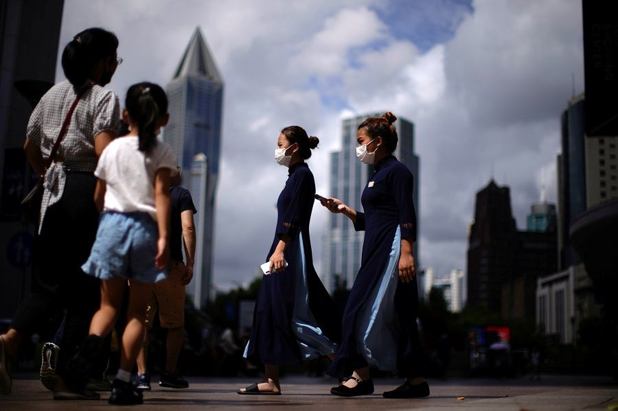 People wearing protective masks walk on a street in Shanghai, China, 5 August 2021. (Aly Song/Reuters)