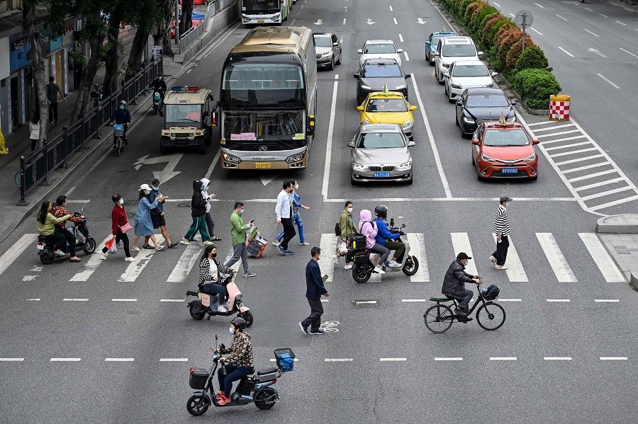 This photo taken on 30 November 2022 shows people walking across a street in Haizhu district, Guangzhou, Guangdong province, China, following the easing of Covid-19 restrictions in the city. (CNS/AFP)