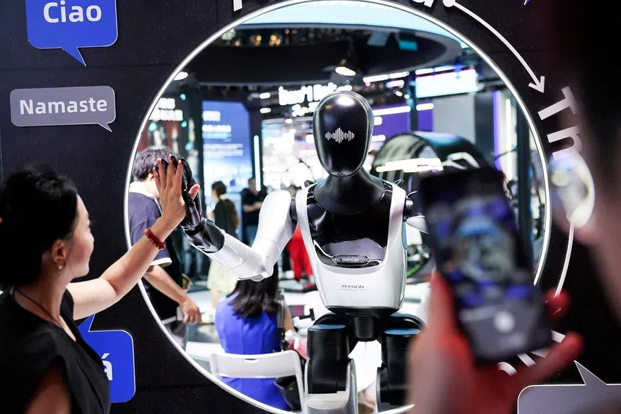 A visitor high-fives a humanoid robot at the Keenon Robotics booth during the World Artificial Intelligence Conference (WAIC) in Shanghai, China, on 18 July 2026.