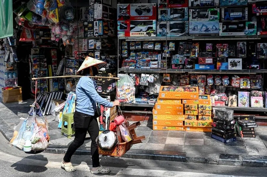 A street food vendor walks past a toy store in Hanoi on 1 June 2026.